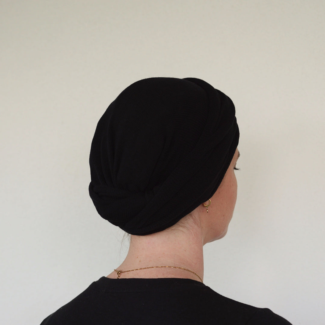 Person wearing a black headscarf against a plain background