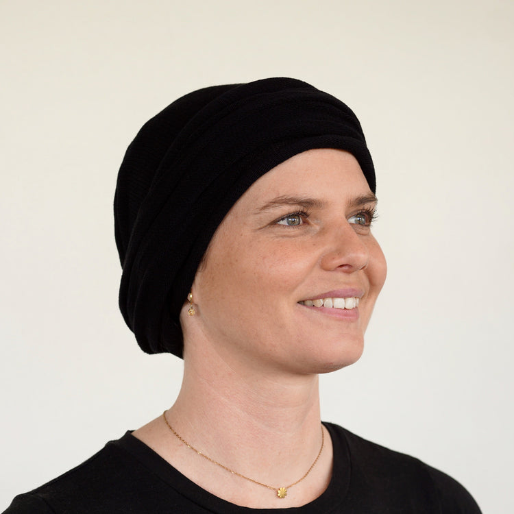 Woman wearing a black headscarf against a plain background