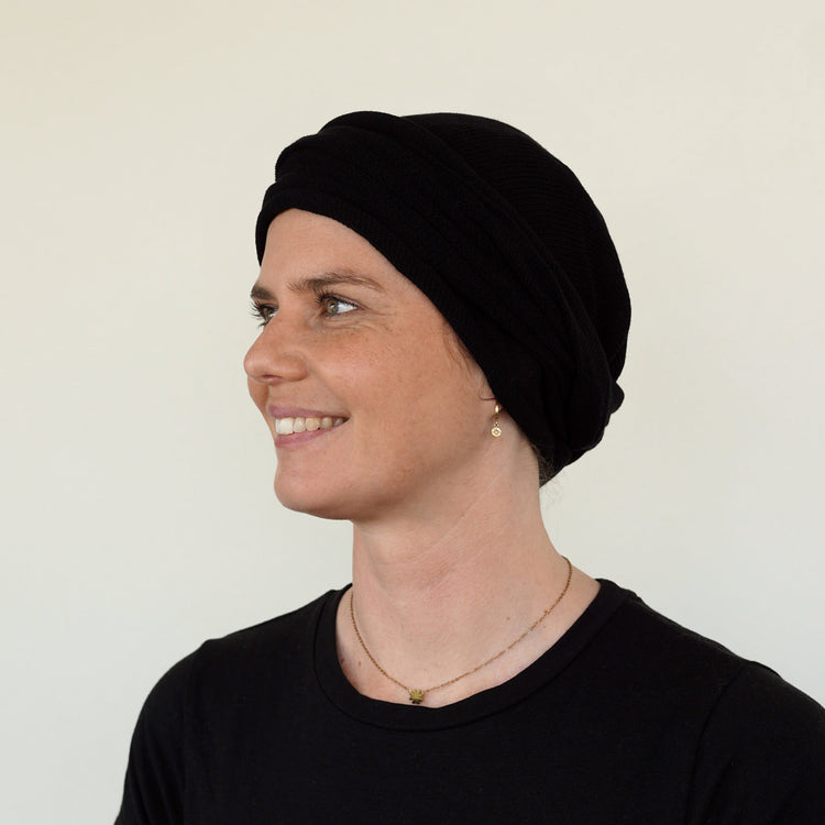Woman wearing a black headscarf against a plain background