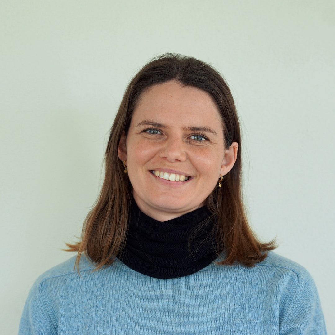 Woman wearing a black scarf and blue sweater against a white background