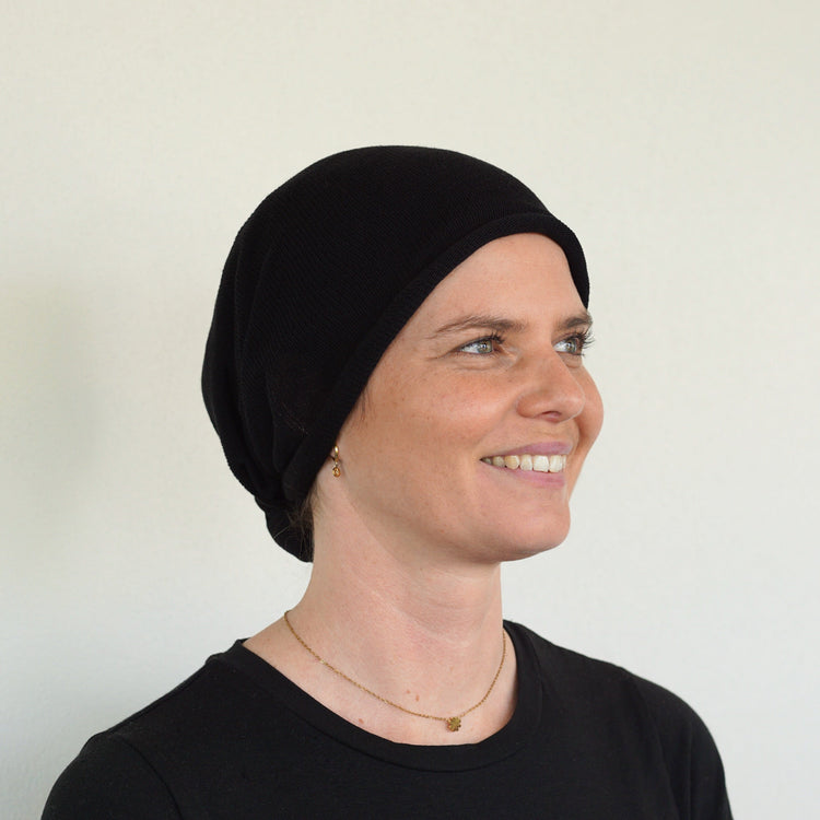 Woman wearing a black headscarf against a plain background
