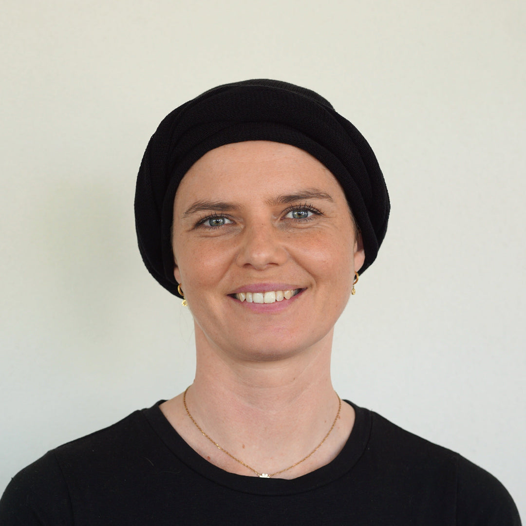 Person wearing a black headscarf against a plain background