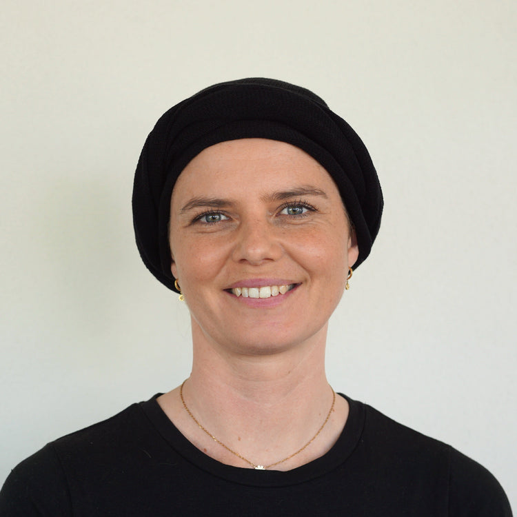 Person wearing a black headscarf against a plain background