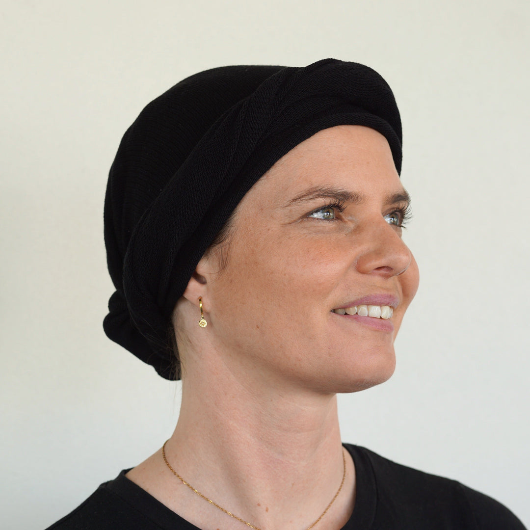 Woman wearing a black headscarf against a plain background