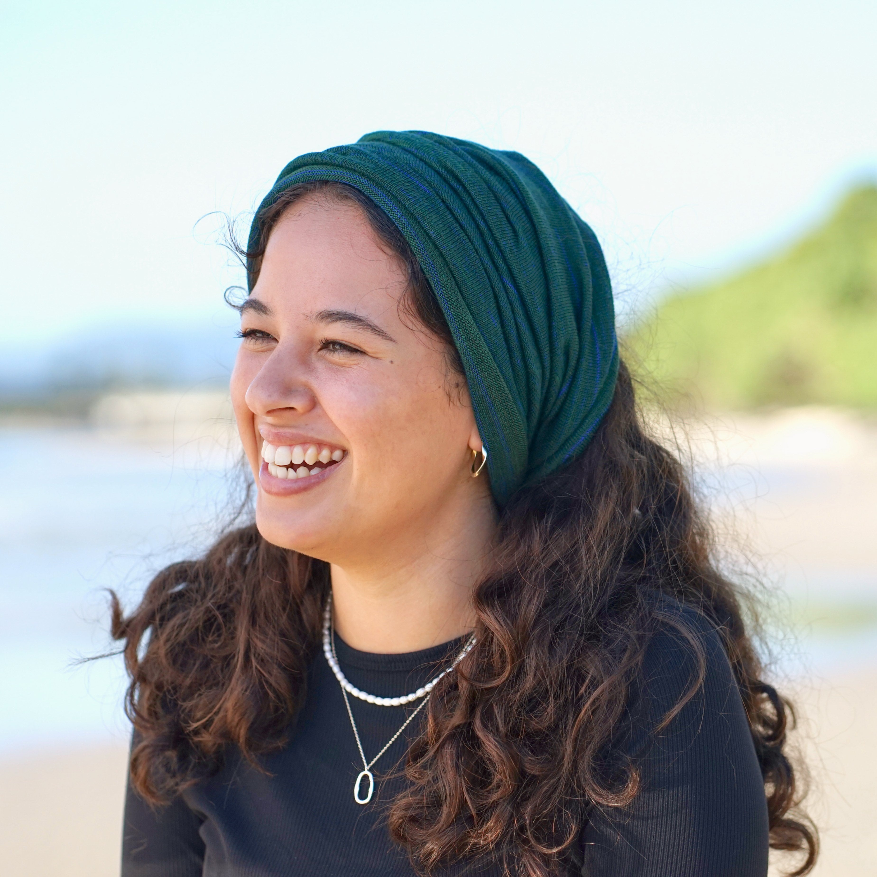 Woman wearing a green headscarf on a beach