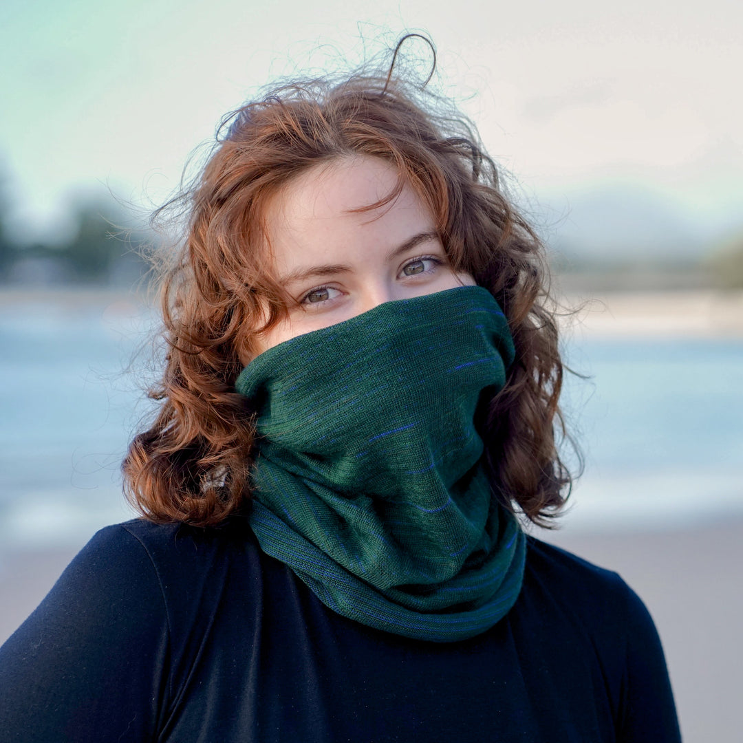 Woman wearing a green scarf covering her mouth with a blurred background